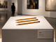 Lo stato dell’arte – Il Valore dell’arte “Tre”. Tre semplici matite entrano nello spazio del museo. La materia è rimasta la stessa; intorno a loro comincia a costruirsi il riconoscimento dell’opera. (Immagine creata con IA – Orchestratore Eko.)